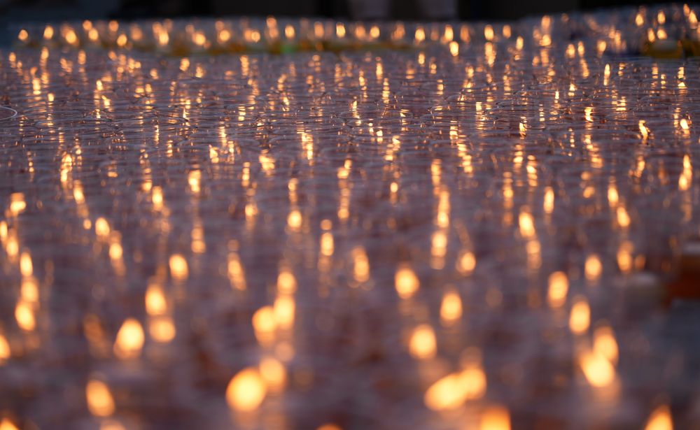 A sea of lit diyas glowing at dusk