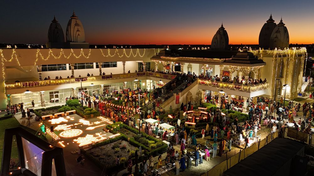 Radha Krishna Temple at dusk, its courtyard lit with diyas